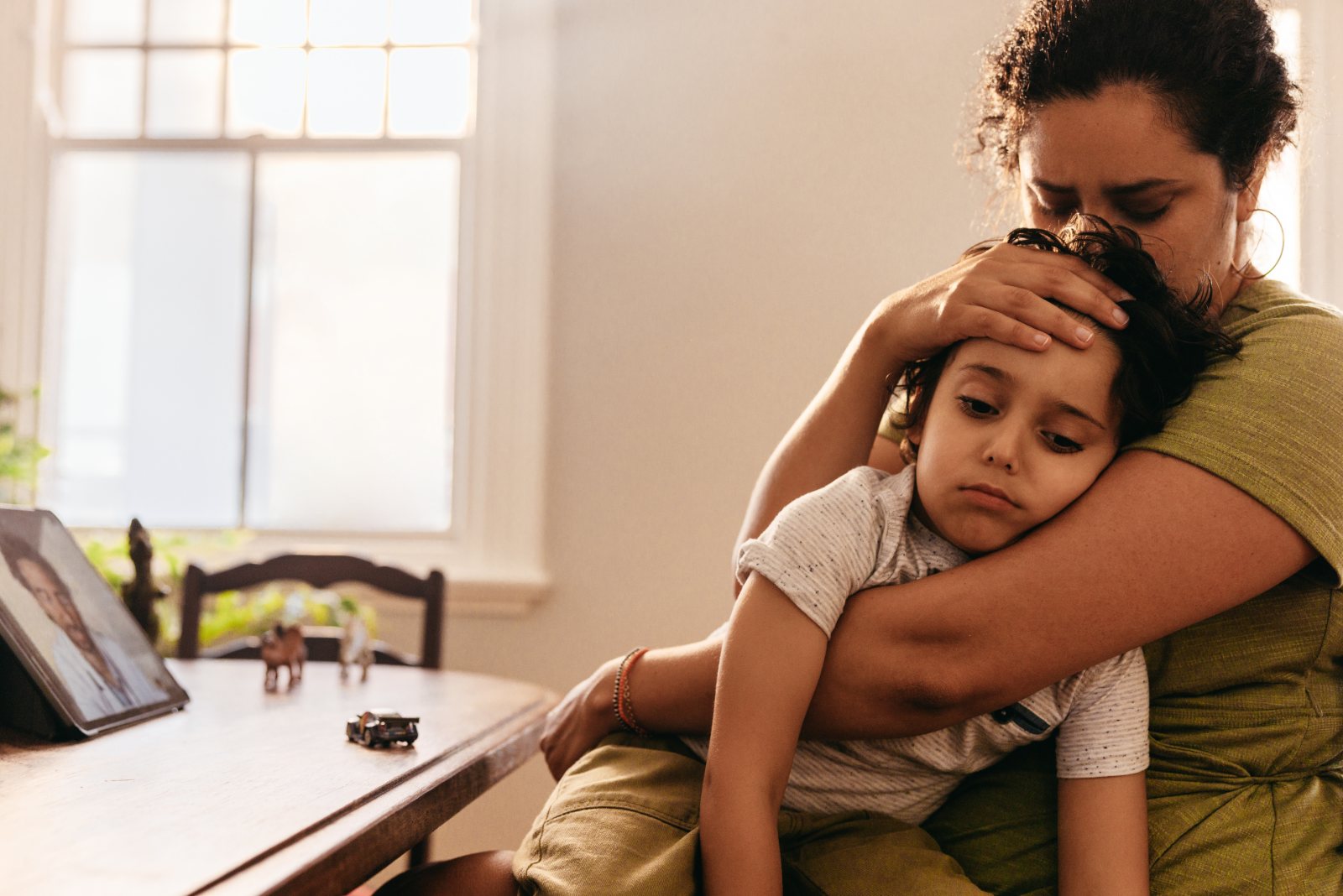 A mother holds her sick child close and feels his forehead