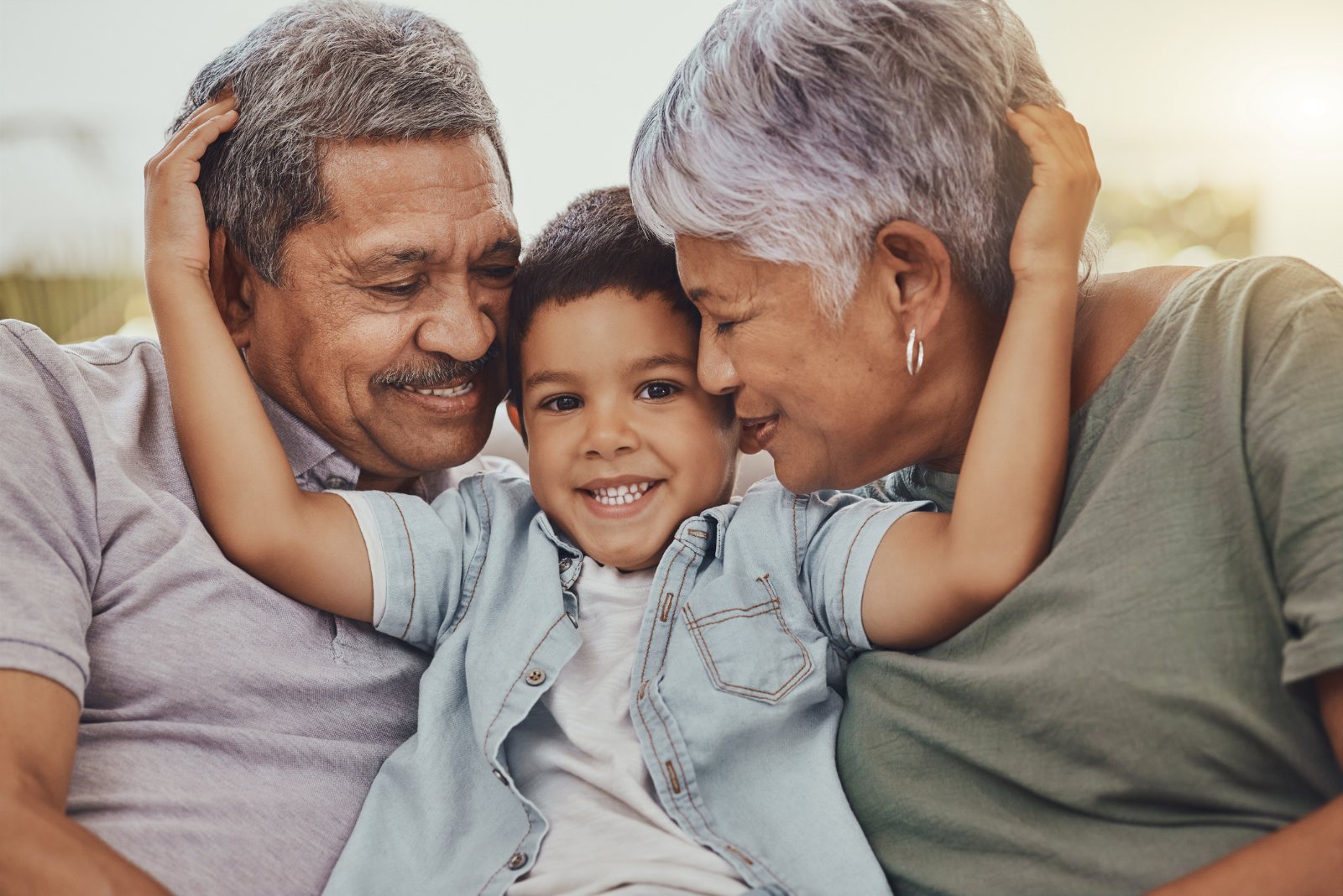 Smiling grandparents hug their young grandson